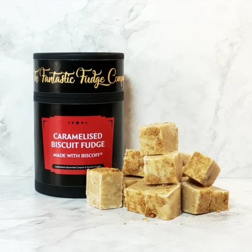 A round box of Biscoff fudge with several square pieces of delicious Biscoff fudge placed beside it.
