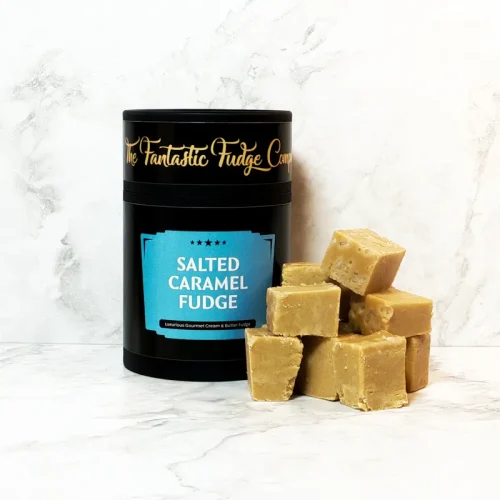 A round box of salted caramel fudge with several square pieces of delicious salted caramel fudge placed beside it.
