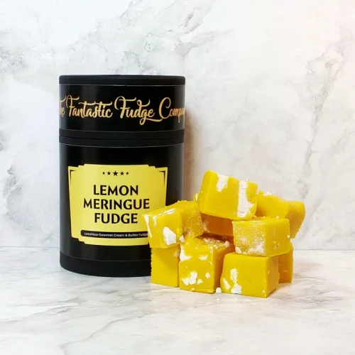 A round box of lemon meringue fudge with several square pieces of delicious lemon meringue fudge placed beside it.