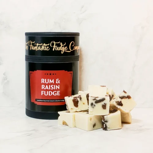 A round box of rum & raisin fudge with several square pieces of delicious rum & raisin fudge placed beside it.